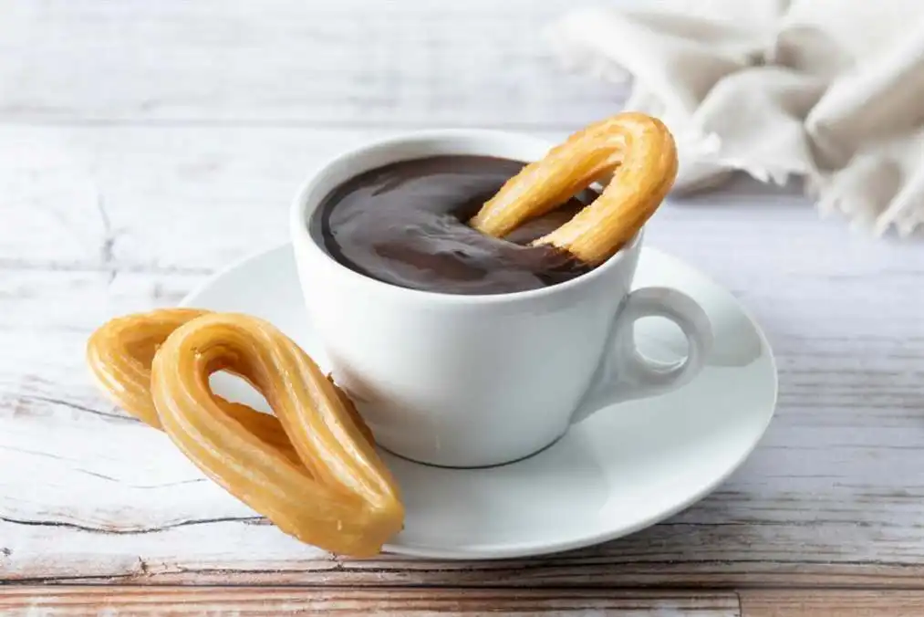 Desayuno tradicional español de churros con chocolate caliente mesa de madera 2 escala 1